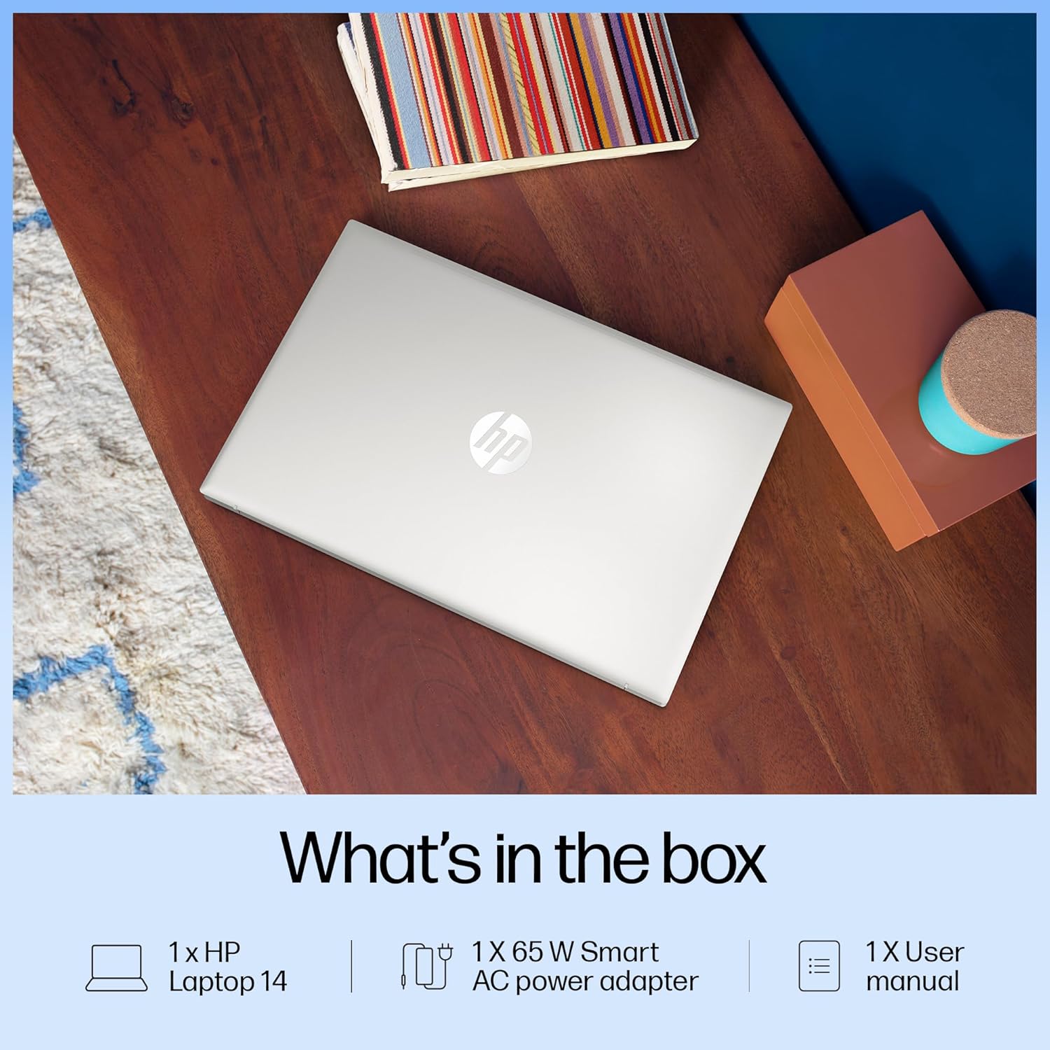 Closed silver HP 14-gr1022TU laptop on wooden desk surrounded by books and decor items